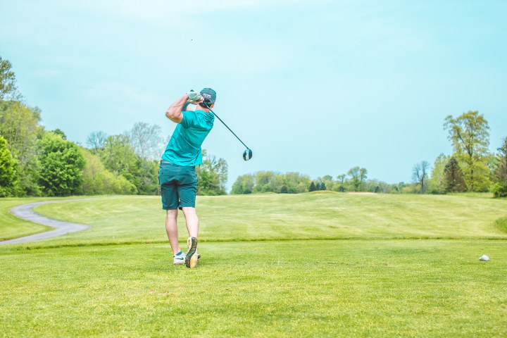 man playing golf on green grass under blue sky